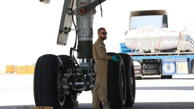 Technici staan onder de geopende motorgondel van een KDC-10 in een onderhoudshangar.