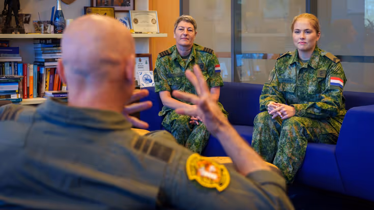 De prinses zit in een kamer met commandant Koninklijke Luchtmacht luitenant-generaal André Steur en commandant Groep Luchtmacht Reserve kolonel Martine Verhulst.