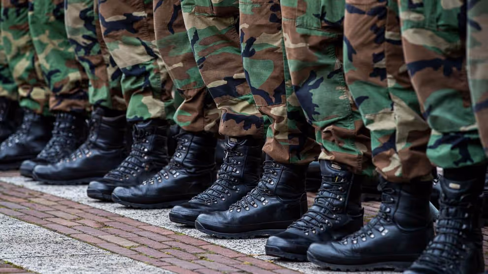 Close-up van voeten en onderbenen gestoken in legerkisten en camouflage kleding.