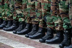Close-up van voeten en onderbenen gestoken in legerkisten en camouflage kleding.
