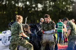 Mannelijke  en vrouwelijke militairen zijn bezig met zandzakken.