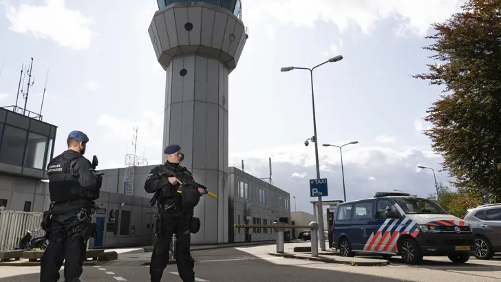 2 marechaussees staan voor de ingang van een luchthaven.