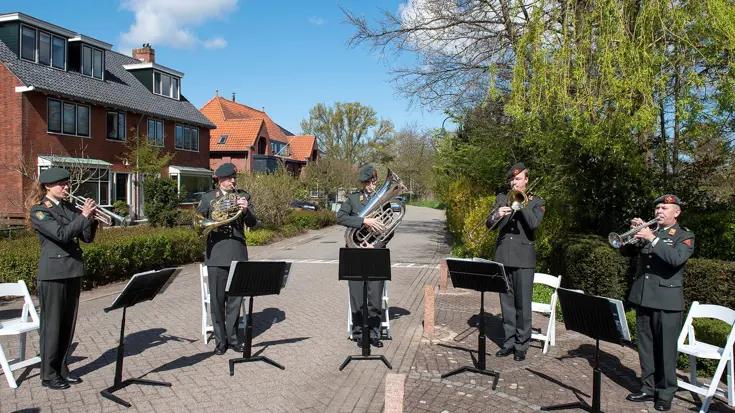Koperkwintet posteert buiten met muziekinstrumenten.