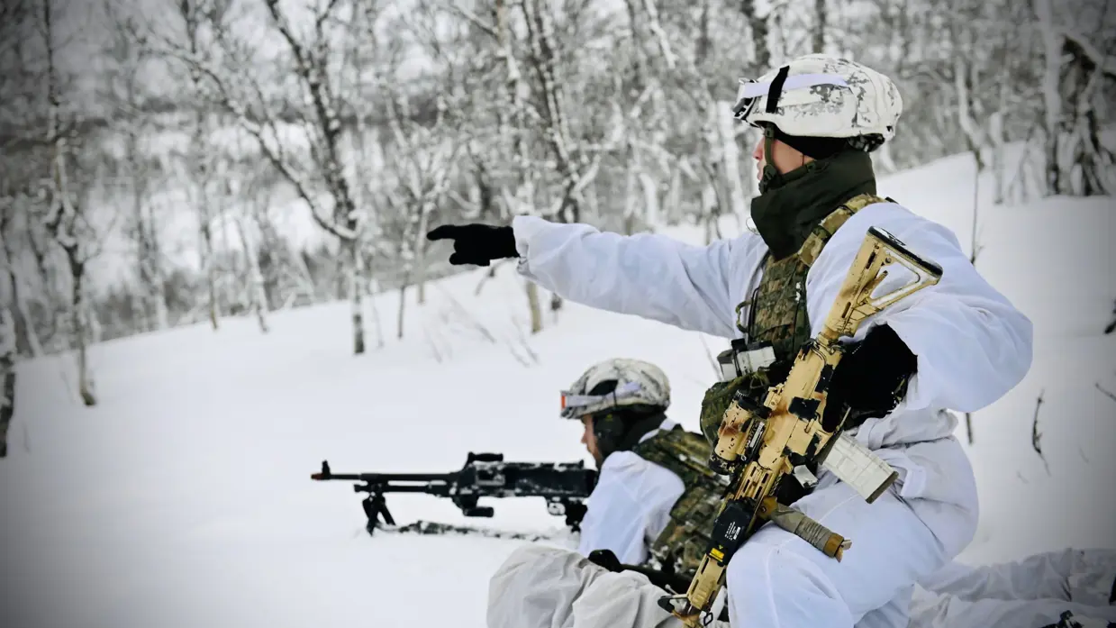 2 militairen in witte kleding op patrouille in de sneeuw.