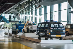 Voertuigen van de marechaussee op de museumvloer. Op de voorgrond een deel van een vliegtuig.