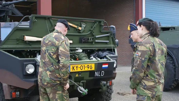2 leerlingen bekijken de motor van een gepantserd voertuig.