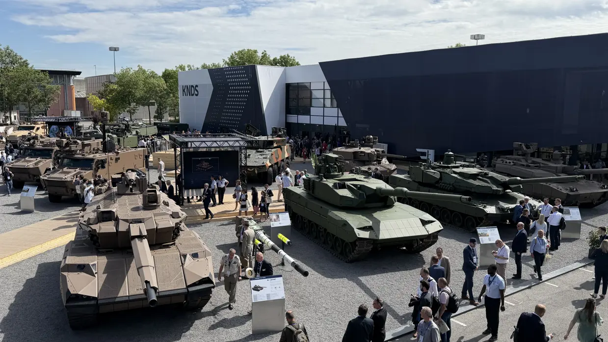  Een overzichtsshot van de Eurosatory met allerlei voertuigen op de voorgrond en de 2A8.