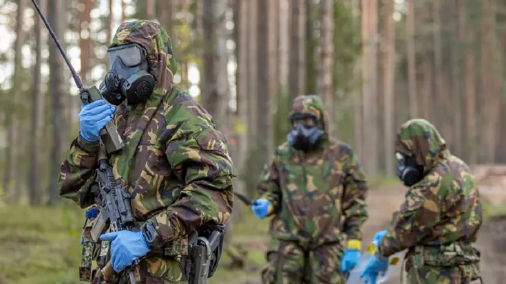 3 militairen met gasmaskers op in bos bij oefening in Litouwen. 