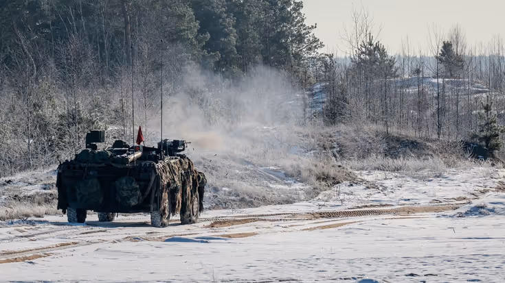 Militair voertuig rijdt door een besneeuwd landschap.