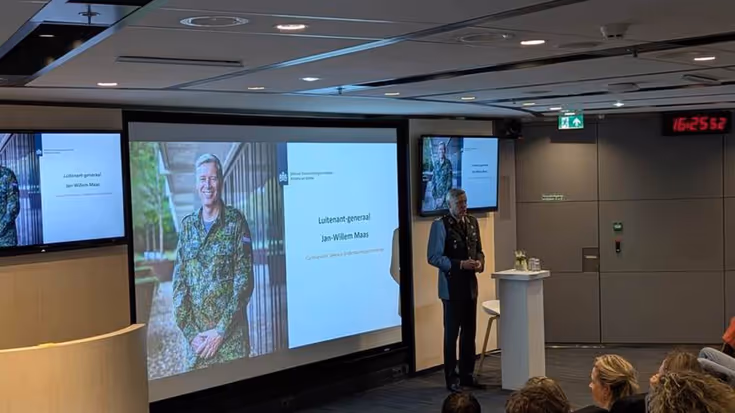 Militair spreekt zaal toe.