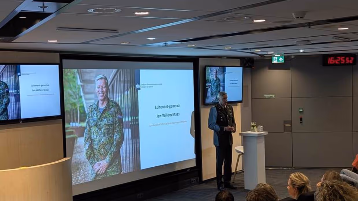 Militair spreekt zaal toe.