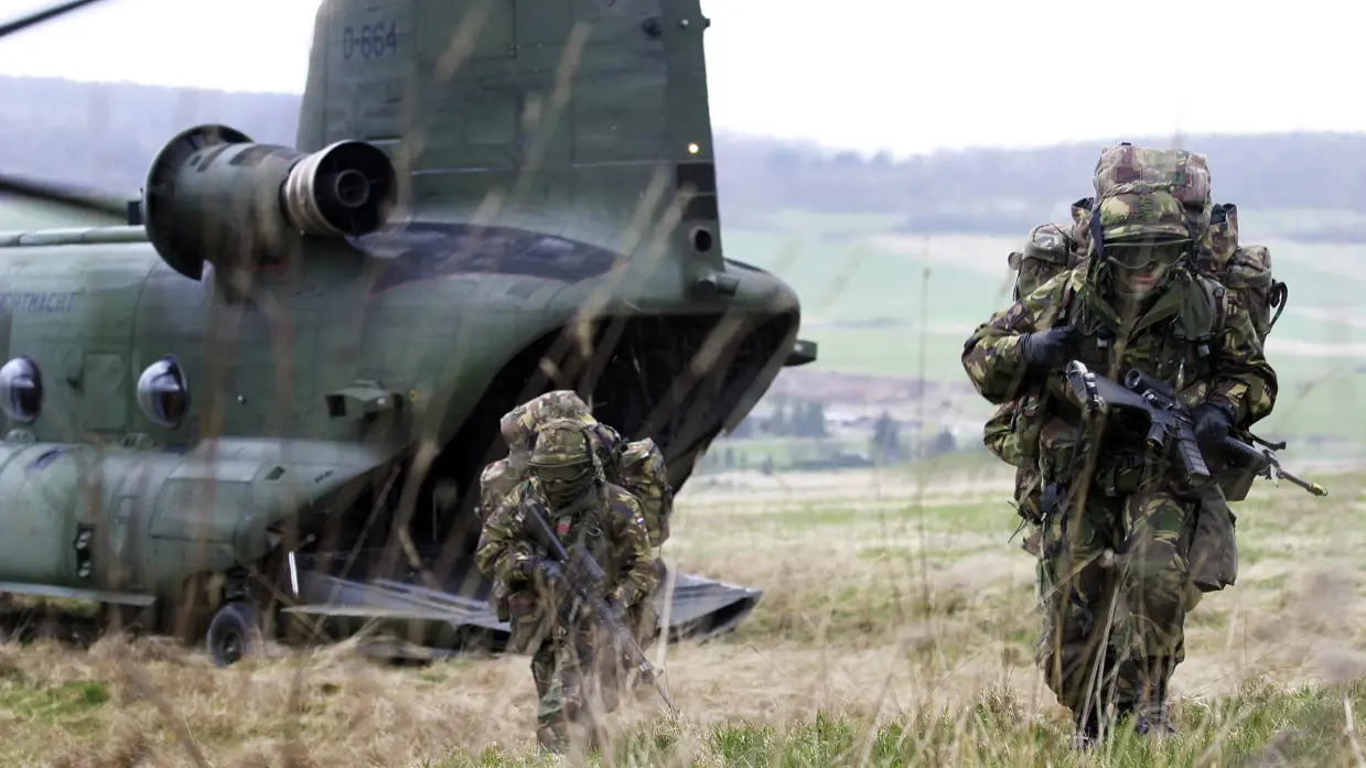 Luchtmobiele militairen zoeken dekking na uit een Chinook-helikopter te zijn gedropt.