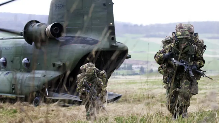 Luchtmobiele militairen zoeken dekking na uit een Chinook-helikopter te zijn gedropt.