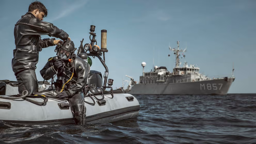 Militair in duikpak op rubberbootje maakt zich klaar voor duik in zee.