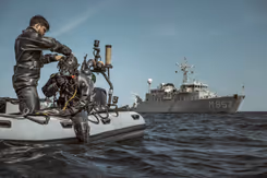 Militair in duikpak op rubberbootje maakt zich klaar voor duik in zee.