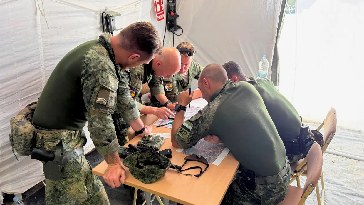 Militairen gebogen over een kaart tijdens oefening Angel Guardian.