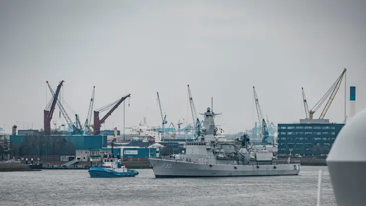 Een marineschip vaart de haven binnen.