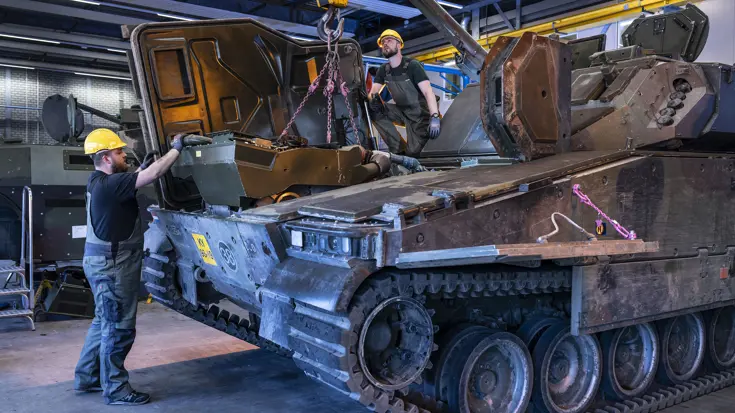 Militaire monteurs bezig met het onderhoud aan een CV90 infanteriegevechtsvoertuig.