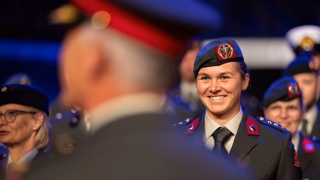 Een militair staat met een grote glimlach te wachten op de medaille