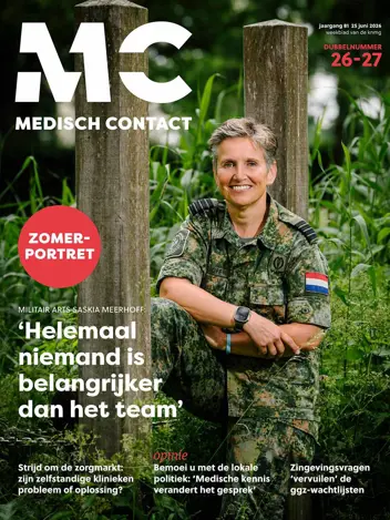 De cover van Medisch Contact toont een glimlachende militair arts in camouflagekleding, zittend tussen groene planten en houten palen.