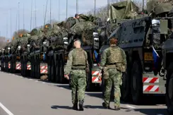 Twee militairen lopen langs een rij gevechtsvoertuigen