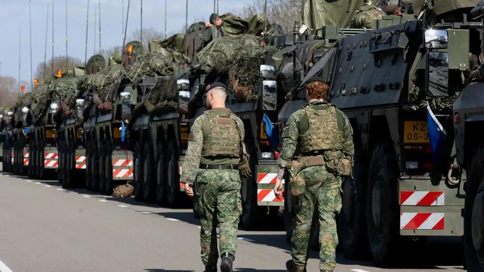Twee militairen lopen langs een rij gevechtsvoertuigen