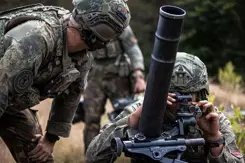 Militairen in gevechtstenue bedienen een mortier.