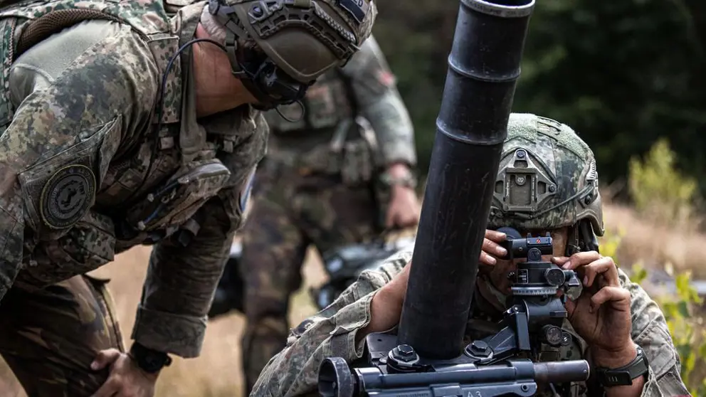 Militairen in gevechtstenue bedienen een mortier.