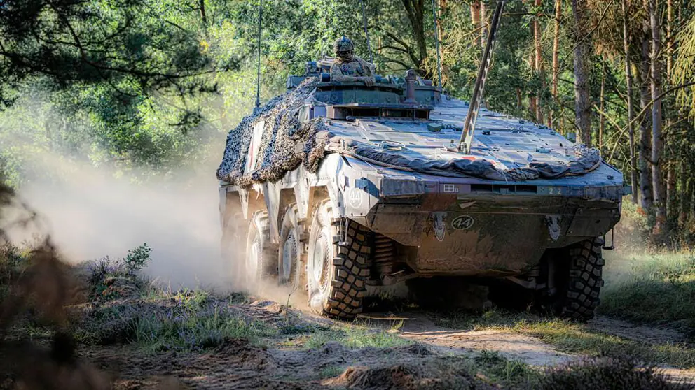 Militair voertuig in bosrijke omgeving.