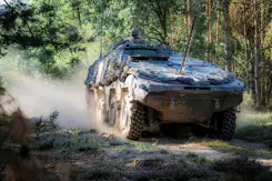 Militair voertuig in bosrijke omgeving.