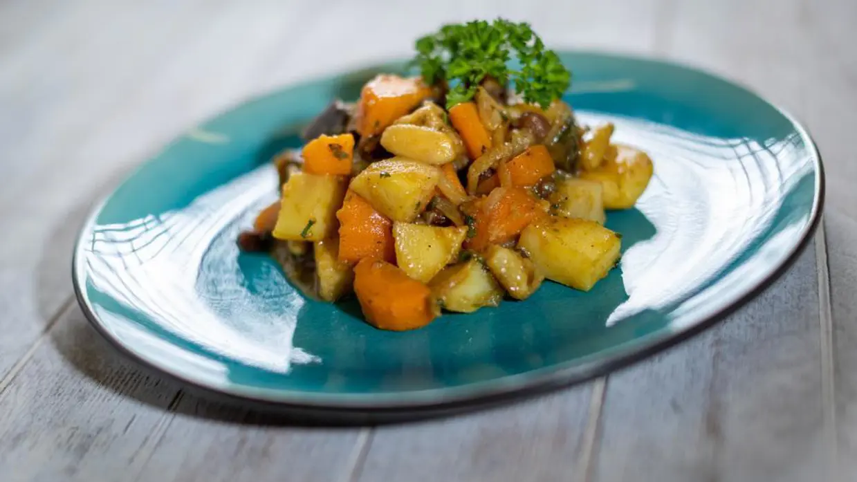 Op de linkerfoto een mooi opgemaakt bord met een gerecht dat bestaat uit onder andere aardappel en wortel. Op de rechterfoto snijdt een Paresto-keukenmedewerker een aantal lente-uitjes.