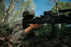 Een militair ligt op de grond met een vuurwapen. 