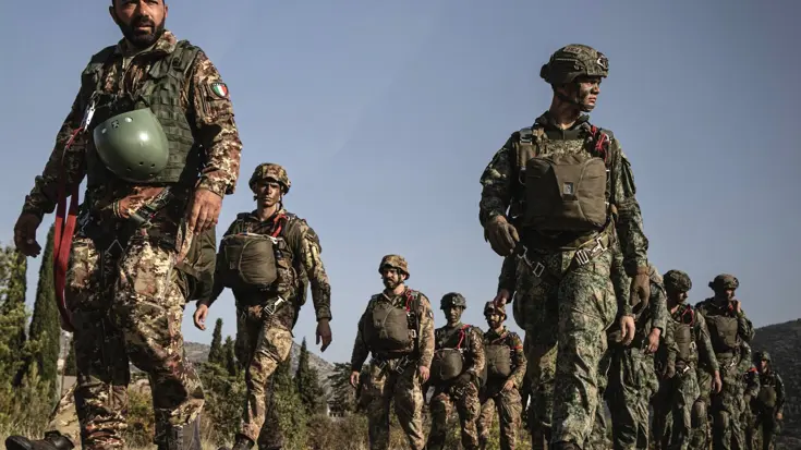  Italiaanse en Nederlandse militairen gekleed in gevechtstenue lopen in twee rijen.