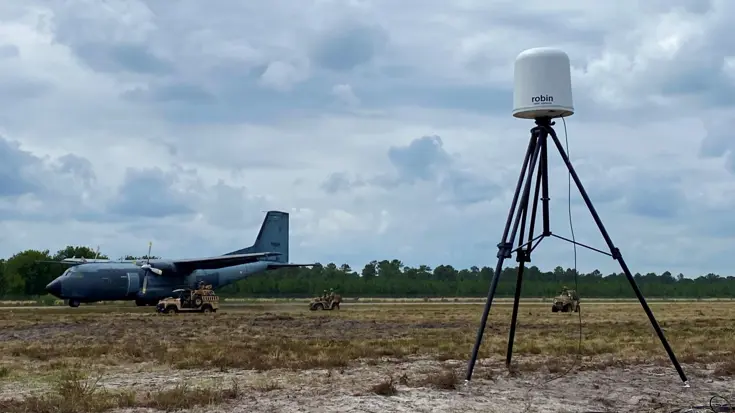  Een radarsysteem in een veld, daarachter een militair vliegtuig.