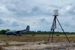 Een vliegtuig op de grond, met daarvoor een antidrone systeem.