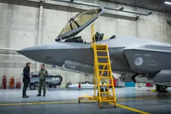 F-35 gevechtsvliegtuig staat in hangar met de cockpit open en een gele trap tegen het toestel.