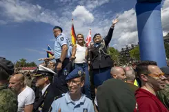 De minister staat met militairen op een boot tijdens de Canal Parade.