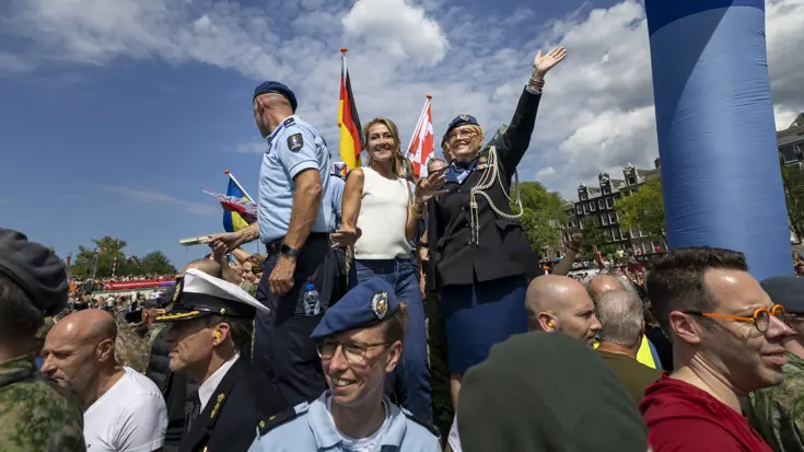 De minister staat met militairen op een boot tijdens de Canal Parade.