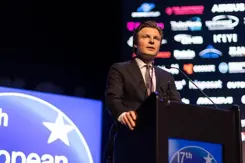 Minister Brekelmans staat achter een katheder.