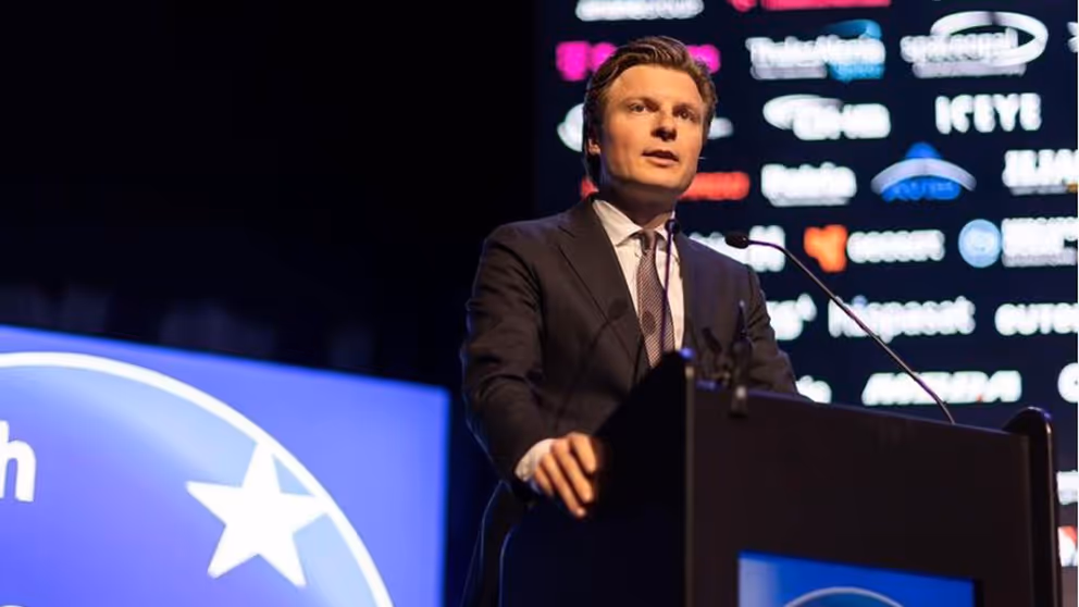 Minister Brekelmans staat achter een katheder.