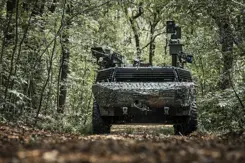 Gecamoufleerd militair voertuig rijdt door een bos