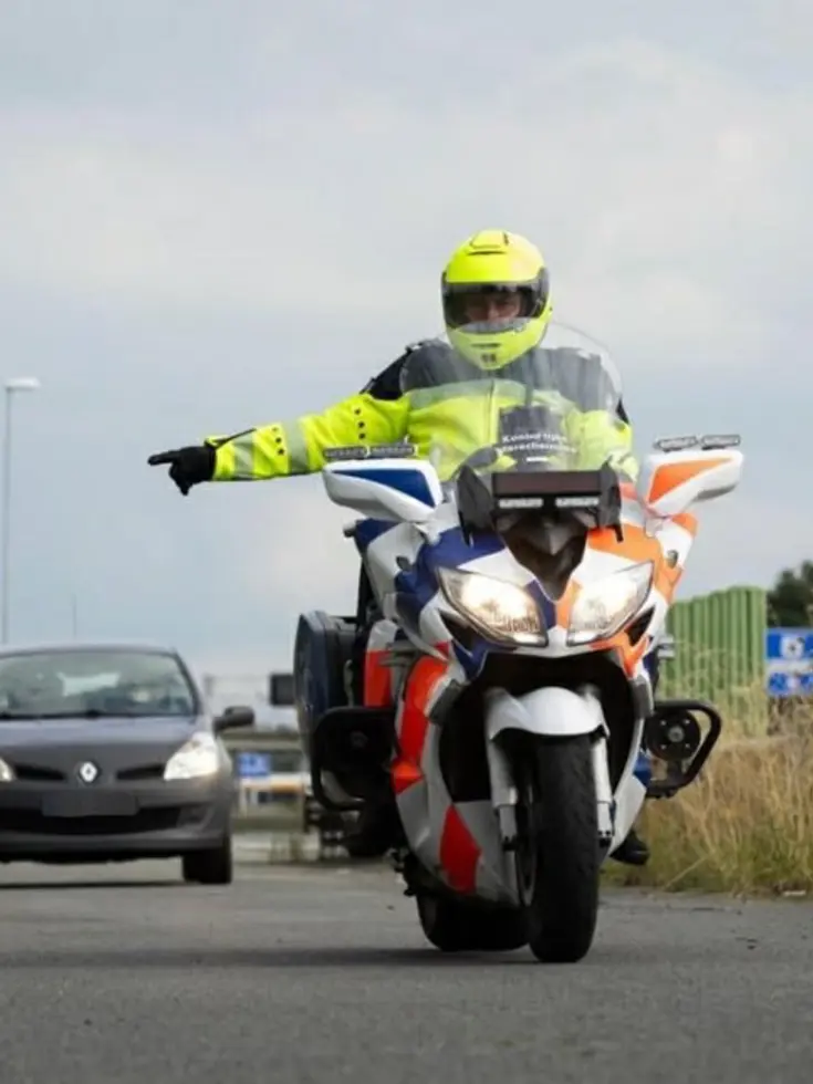 Motorrijder wijst een auto naar de zijkant van de weg