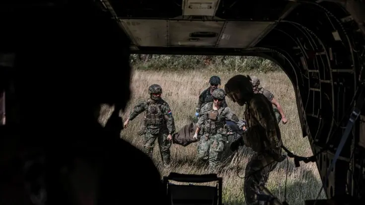Militairen lopen met brancard naar ambulance. Foto gemaakt vanuit de ambu.
