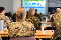 Militairen op de rug gezien tijdens presentatie in vergaderruimte.