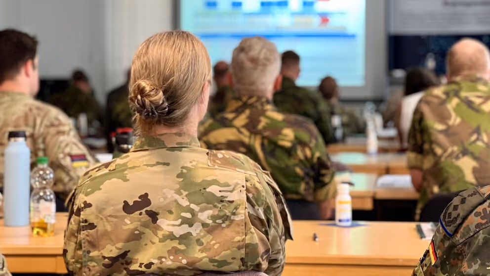 Militairen op de rug gezien tijdens presentatie in vergaderruimte.