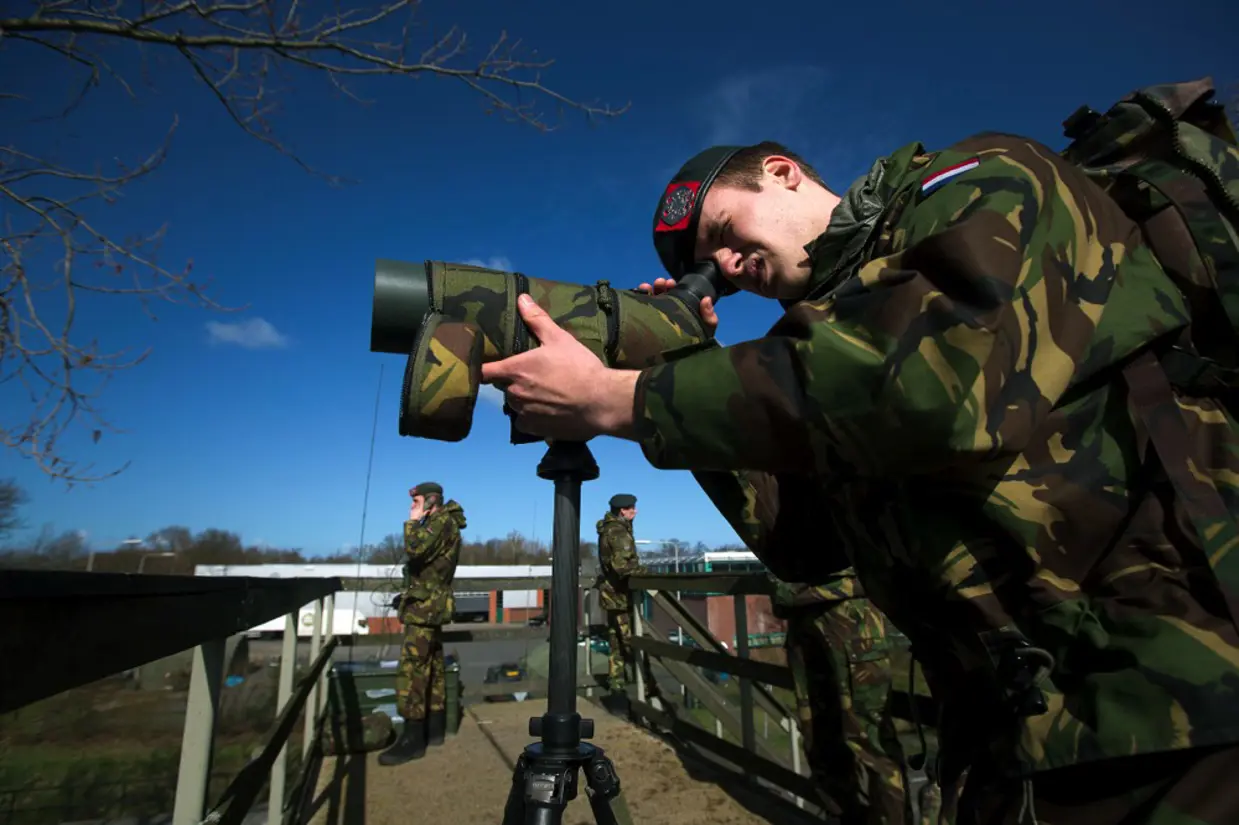 Militairen Korps Nationale Reserve met kijker en radiocontact.