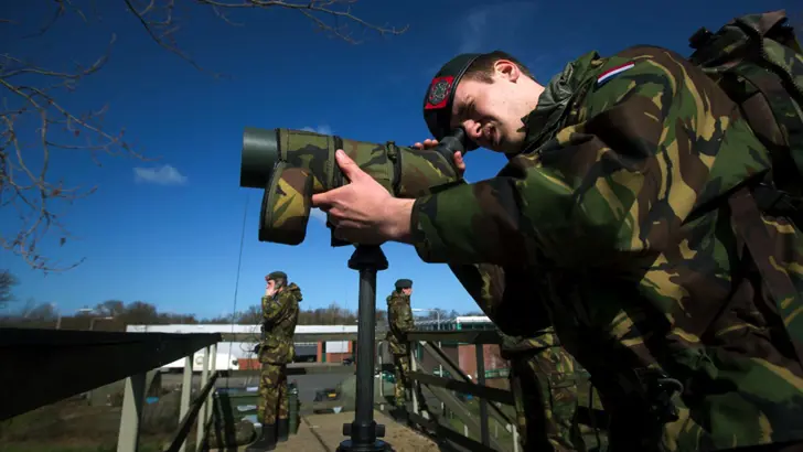 Militairen Korps Nationale Reserve met kijker en radiocontact.