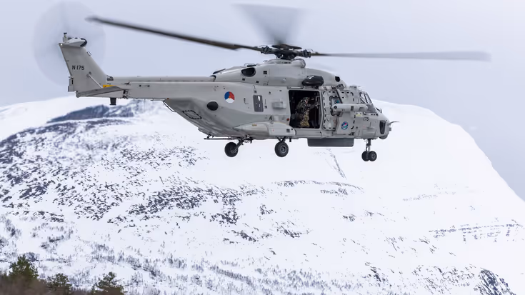 NH90 helikopter in de lucht met op de achtergrond een besneeuwde berg.