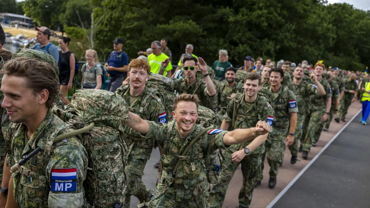 Een groep militairen loopt voorbij en juicht.  