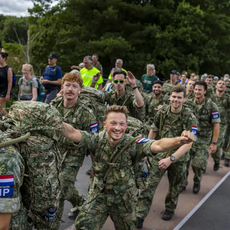 Een groep militairen loopt voorbij en juicht.  
